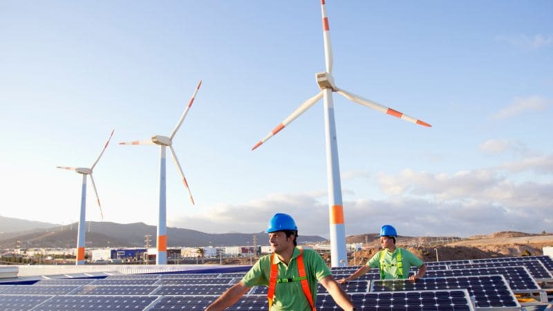 Workers installing wind turbines and solar panels